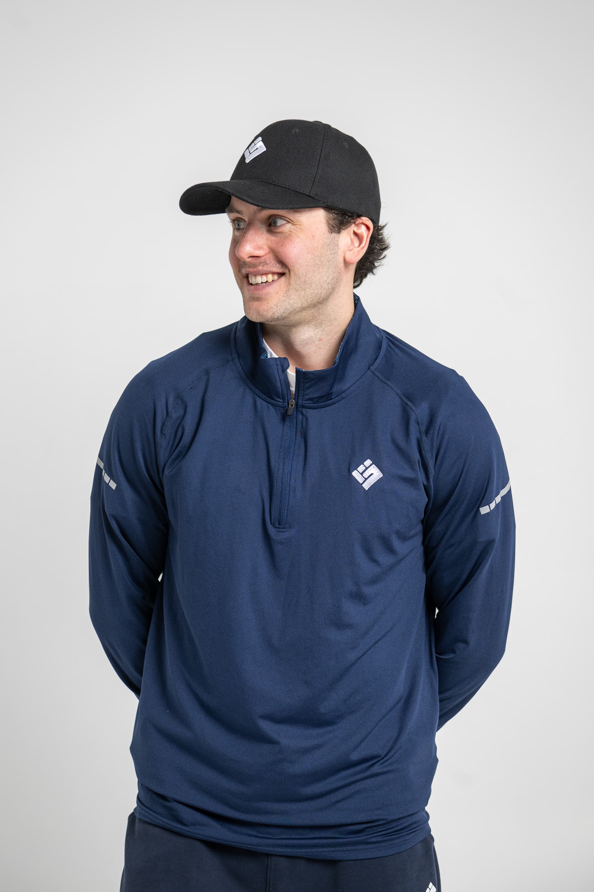 Membre de l'équipe Grasp Performance portant un demi-zip et une casquette aux couleurs de la marque
